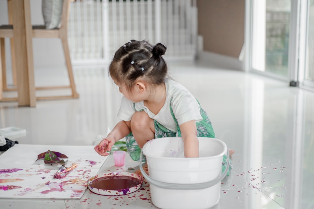 girl sitting beside white bucket