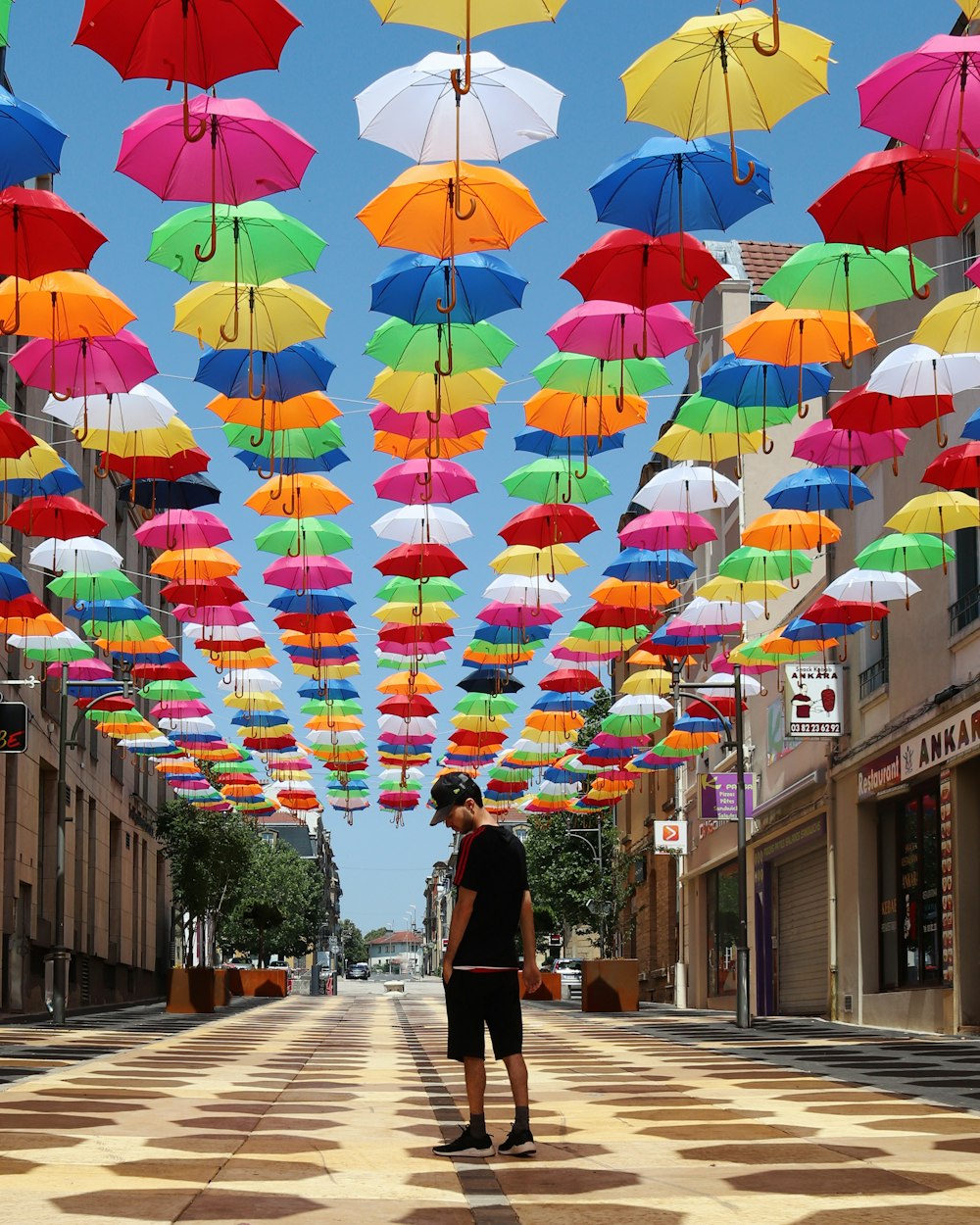 man standing under suspended multicolored umbrellas in street photo – Free  Person Image on Unsplash