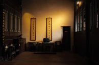 A tranquil indoor space with traditional Chinese calligraphy scrolls and a meditation corner bathed in soft cream light.