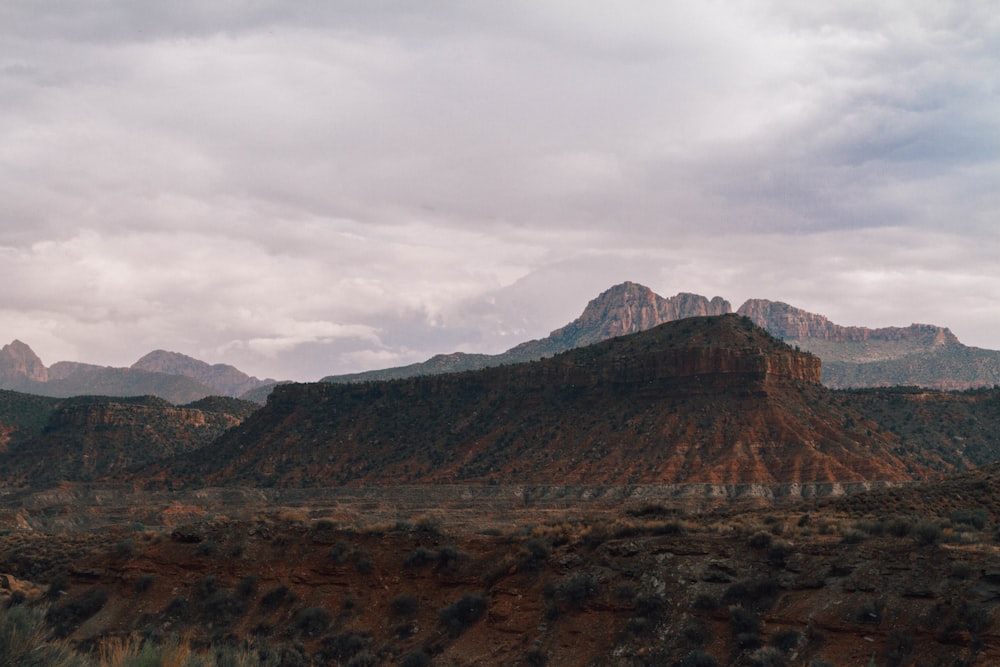 brown mountain range under cloudy sky