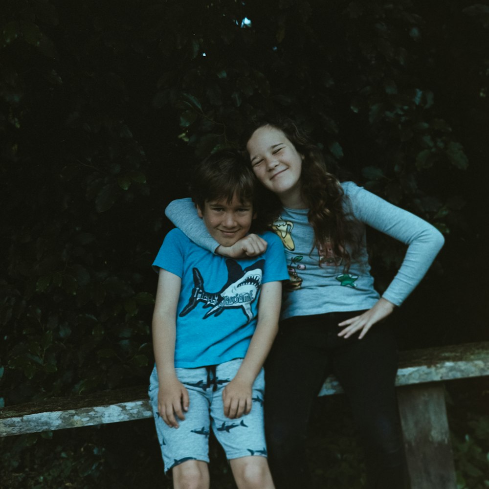 girl hugging boy while sitting on bench