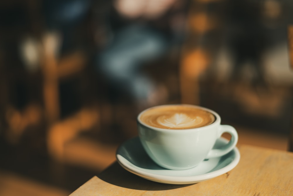 cafe latte in a white ceramic teacup and saucer