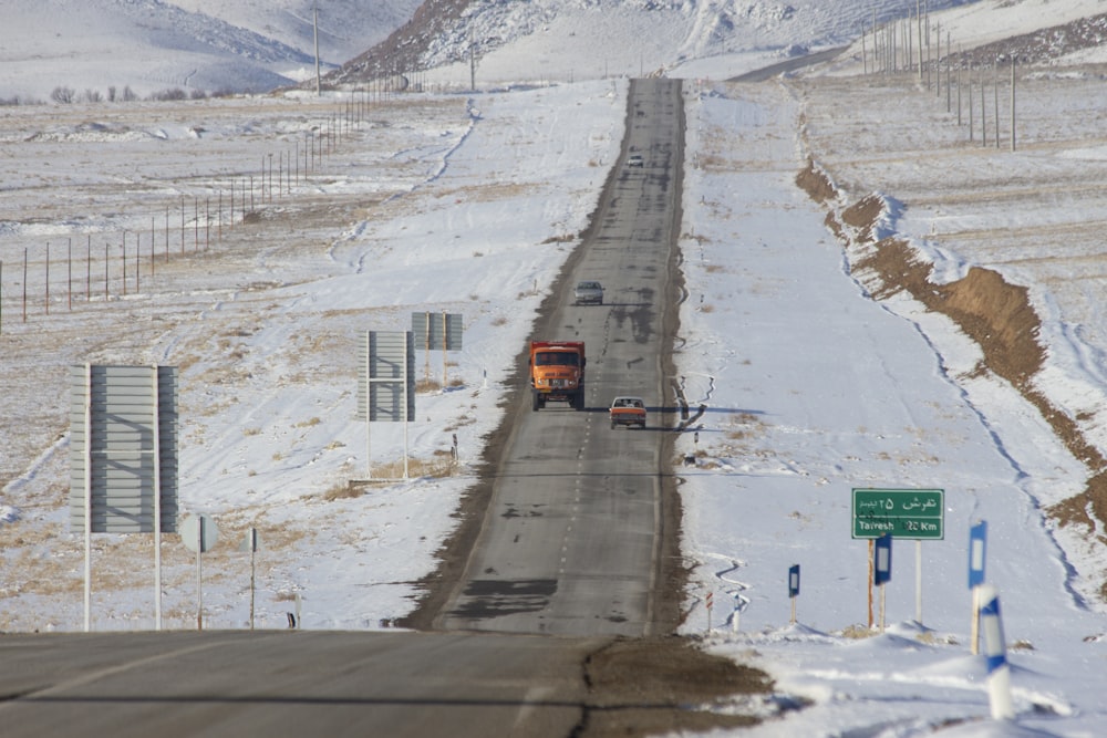 Camión naranja y automóvil que van en direcciones opuestas en carretera recta