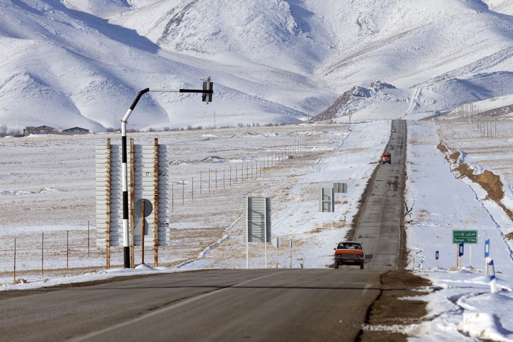 auto che passa sulla strada tra il campo di neve