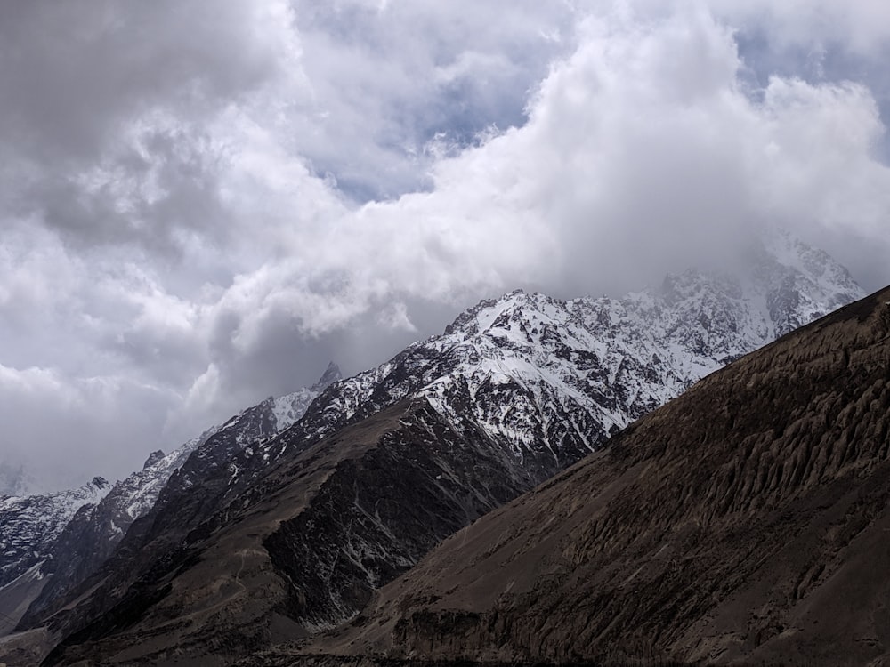grey clouds over snow capped mountain peak