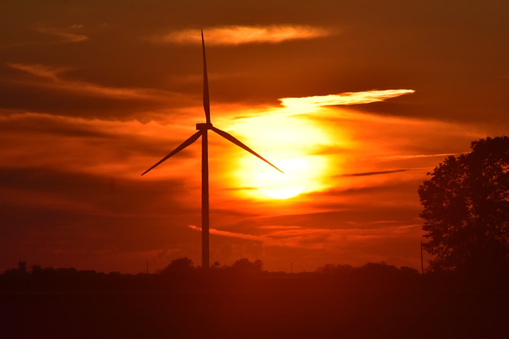 silhouette of windmill under crimson sky at sunset