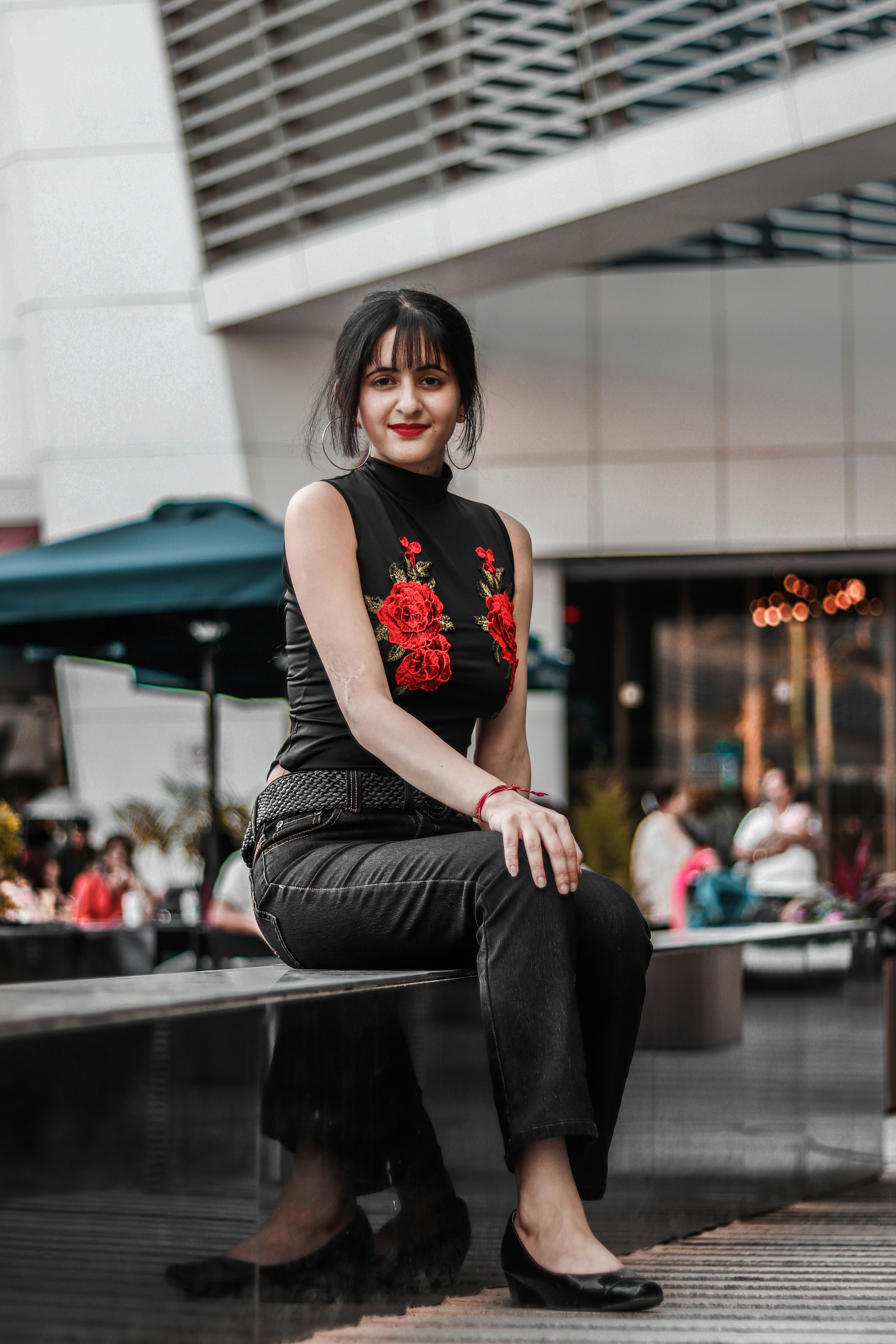 woman in black-and-red floral turtleneck top sitting outside building near cafe