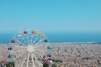 photography of ferris wheel and buildings beside seashore during daytime