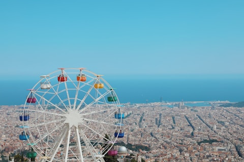 photography of ferris wheel and buildings beside seashore during daytime