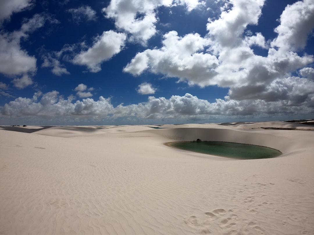 sand dunes with lagoon under cloudy sky,