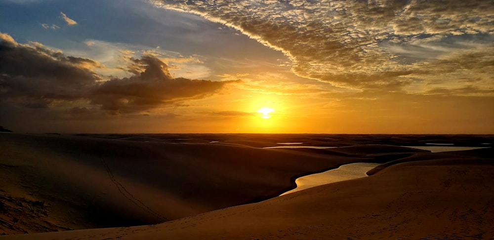 the sun is setting over the sand dunes