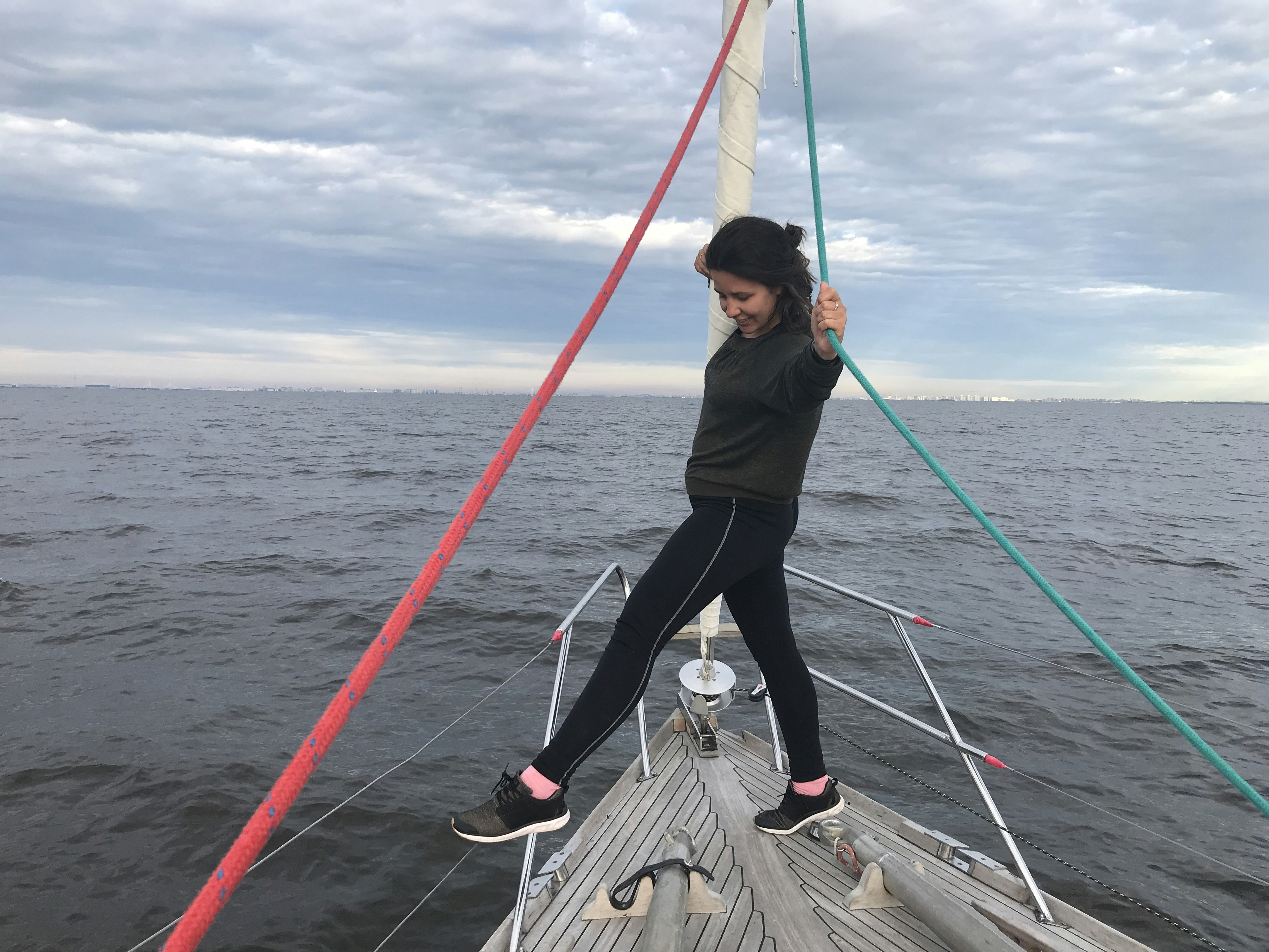 Woman standing on bow of yacht out at sea