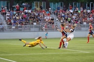 An action shot of a goalkeeper diving to save a ball during a tense match.