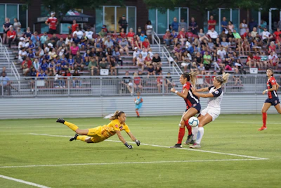 Goalkeeper making a diving save during a tense match moment.