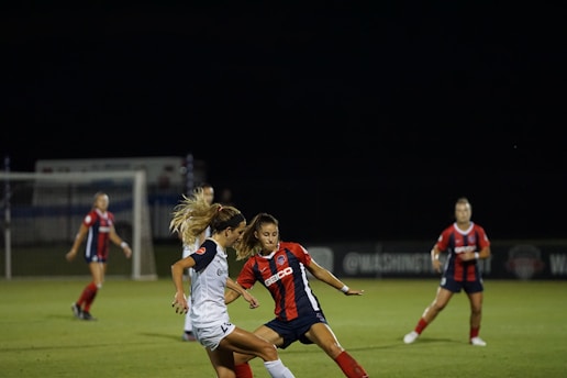 A dynamic women's football match in action under bright stadium lights.