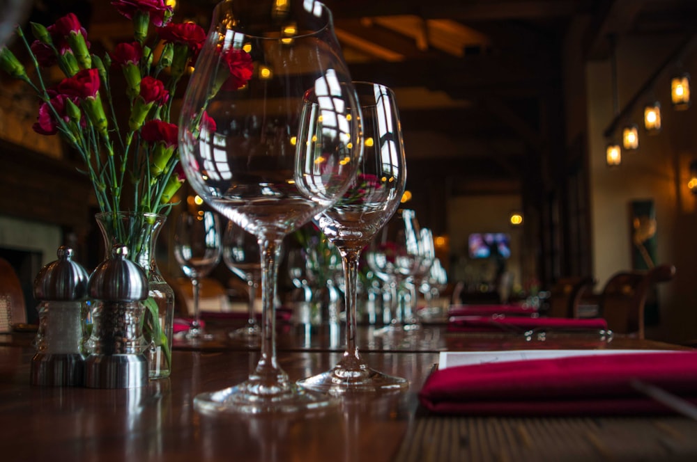 two empty wine glasses beside red flower centerpiece