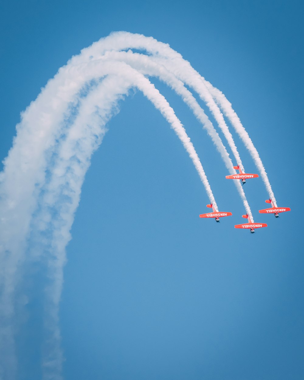 Cuatro aviones rojos y blancos bajo un cielo azul claro