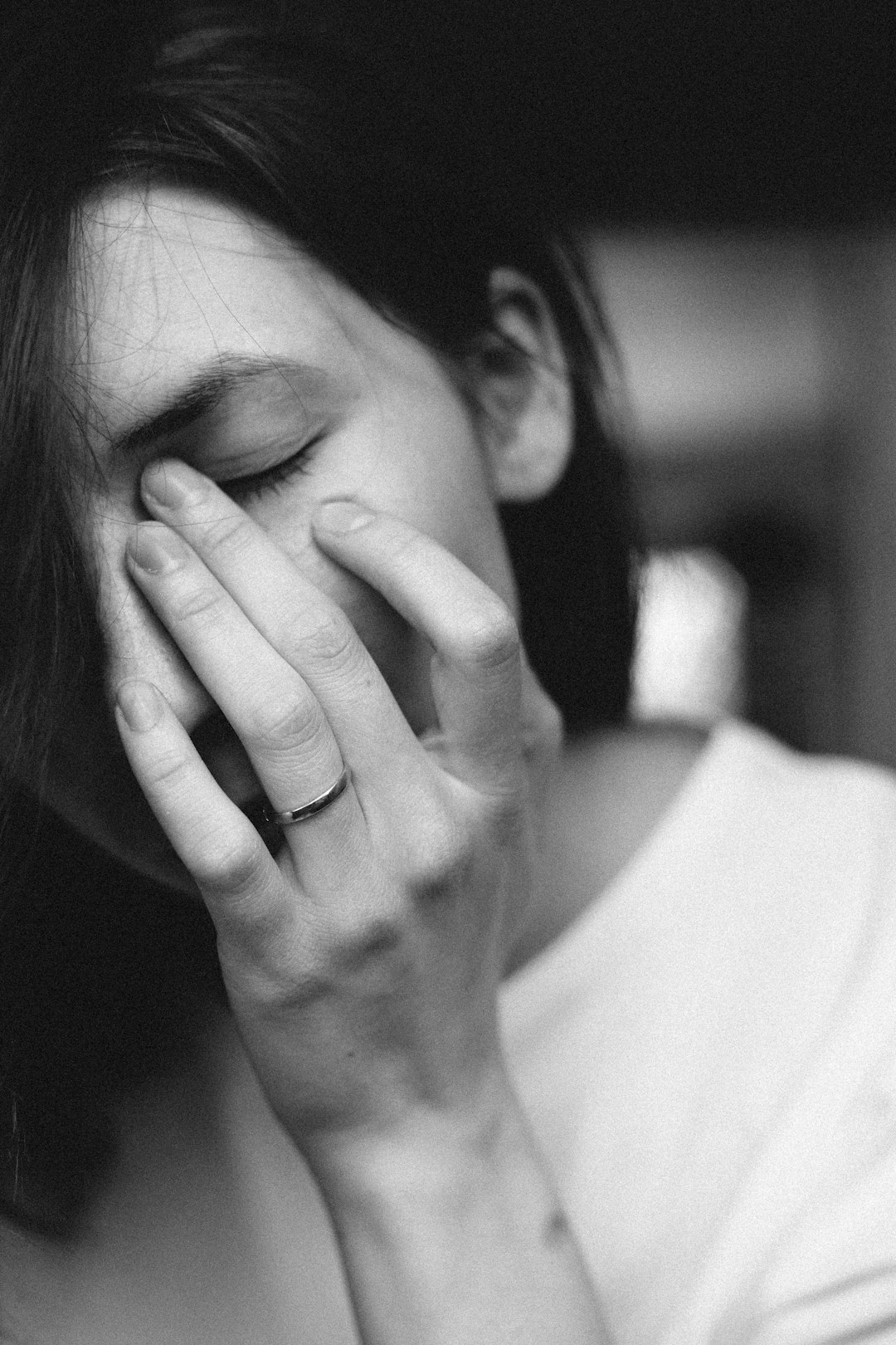 woman in white top with hand on face