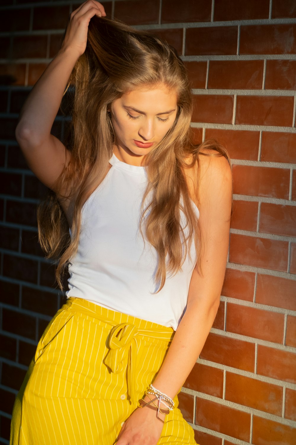 woman standing against the wall pulling her hair while looking down