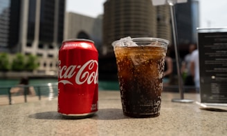 Coca-Cola soda tin can and cup on table close-up photography
