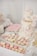 An elegant dessert table features a two-tiered cake adorned with delicate pink and white floral decorations. The cake has 'Engaged' written in gold, symbolizing a celebration. Surrounding it are an assortment of cupcakes topped with pastel-colored frosting, pink and white macarons, and custom sugar cookies with inscriptions. Decorative elements like lace and floral themes add to the sophistication and romantic atmosphere.