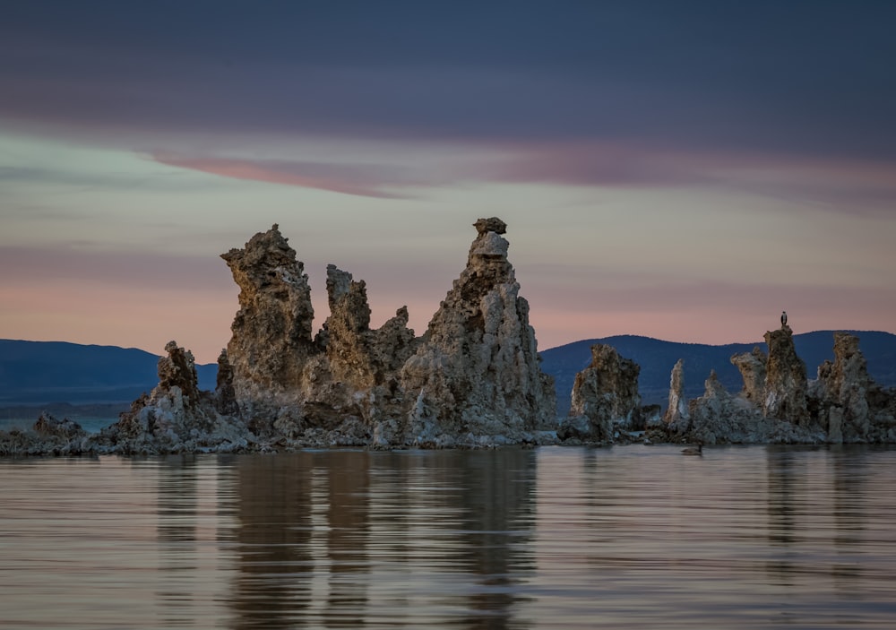 photography of brown rock formation beside body of water during daytime