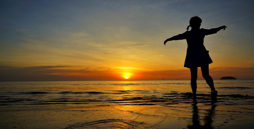 girl standing on seashore during golden hour