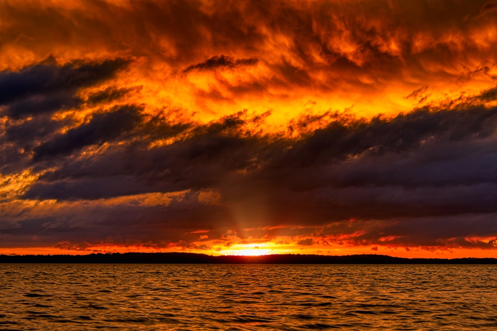 sea under cloudy sky at sun rise