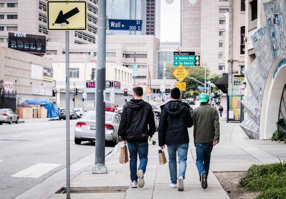 three men walking in road during daytime