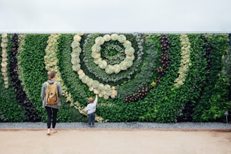 a woman and a child are standing in front of a green wall