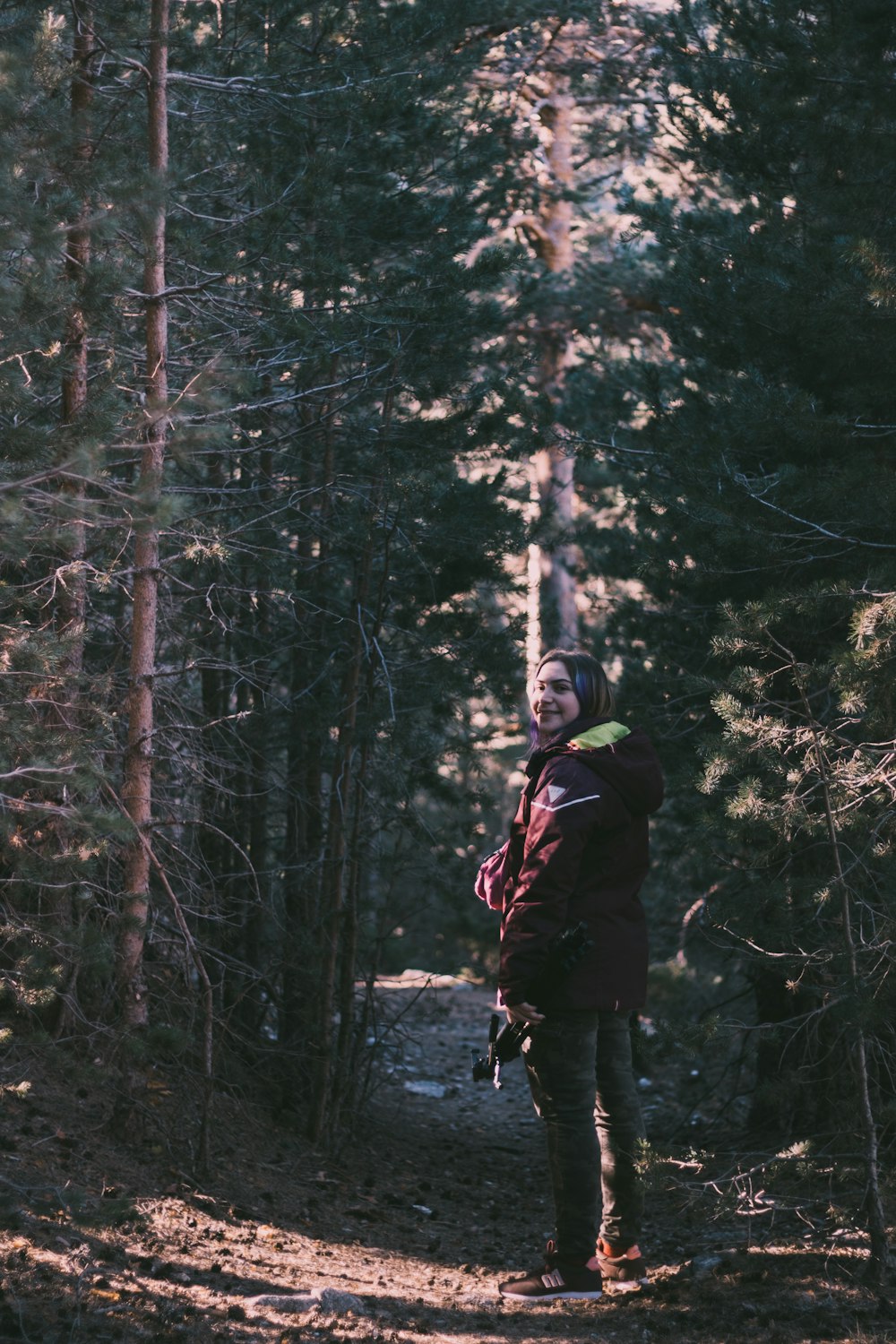 woman standing on dirt road beside trees