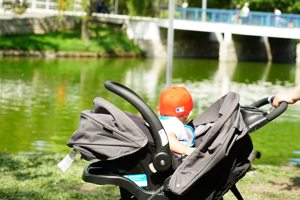 baby sitting on stroller near pond