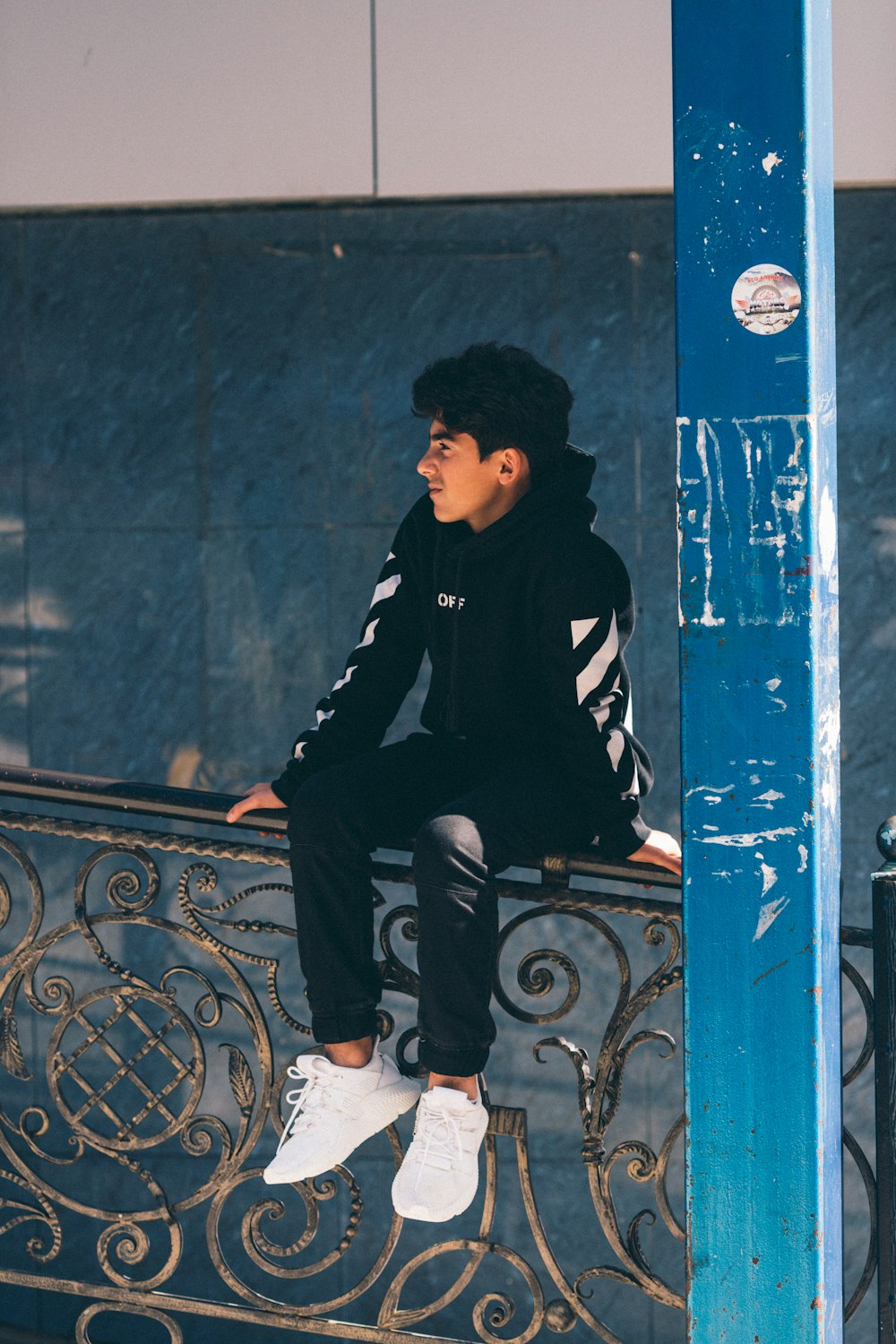 man in black hoodie sitting on metal rail