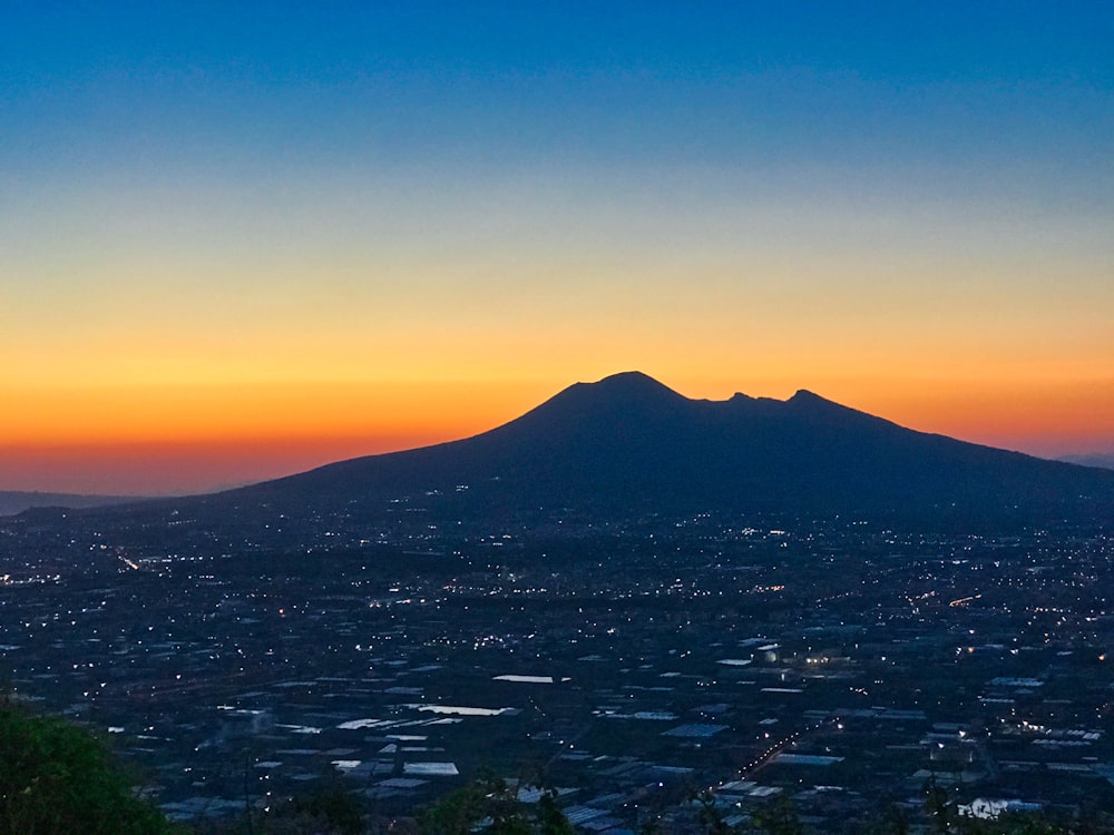 fotografia aerea dell'edificio e della montagna durante il tramonto