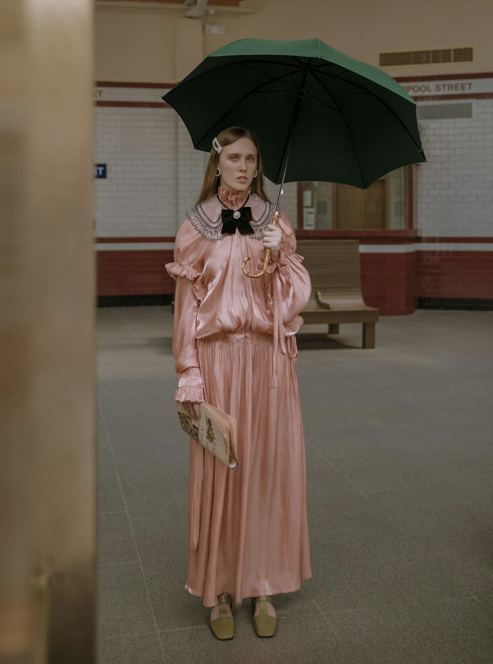 femme en robe rose sous parapluie vert