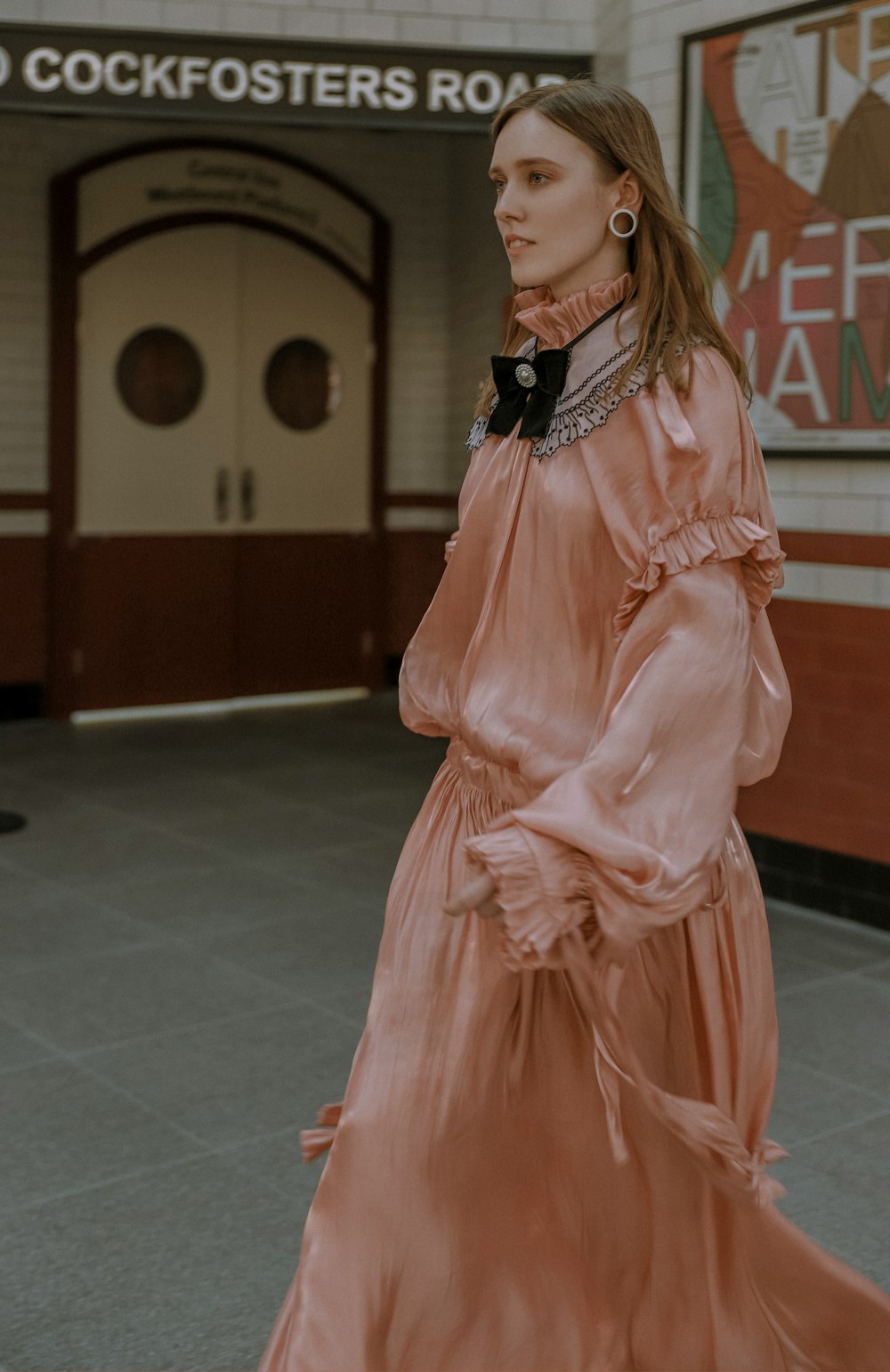 woman wearing pink long-sleeved dress across white door