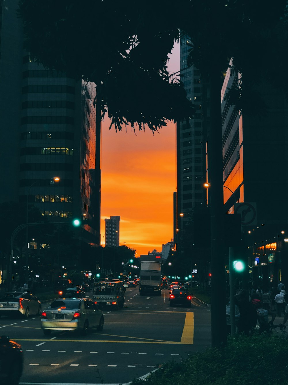 cars in city street under orange sky at sunset