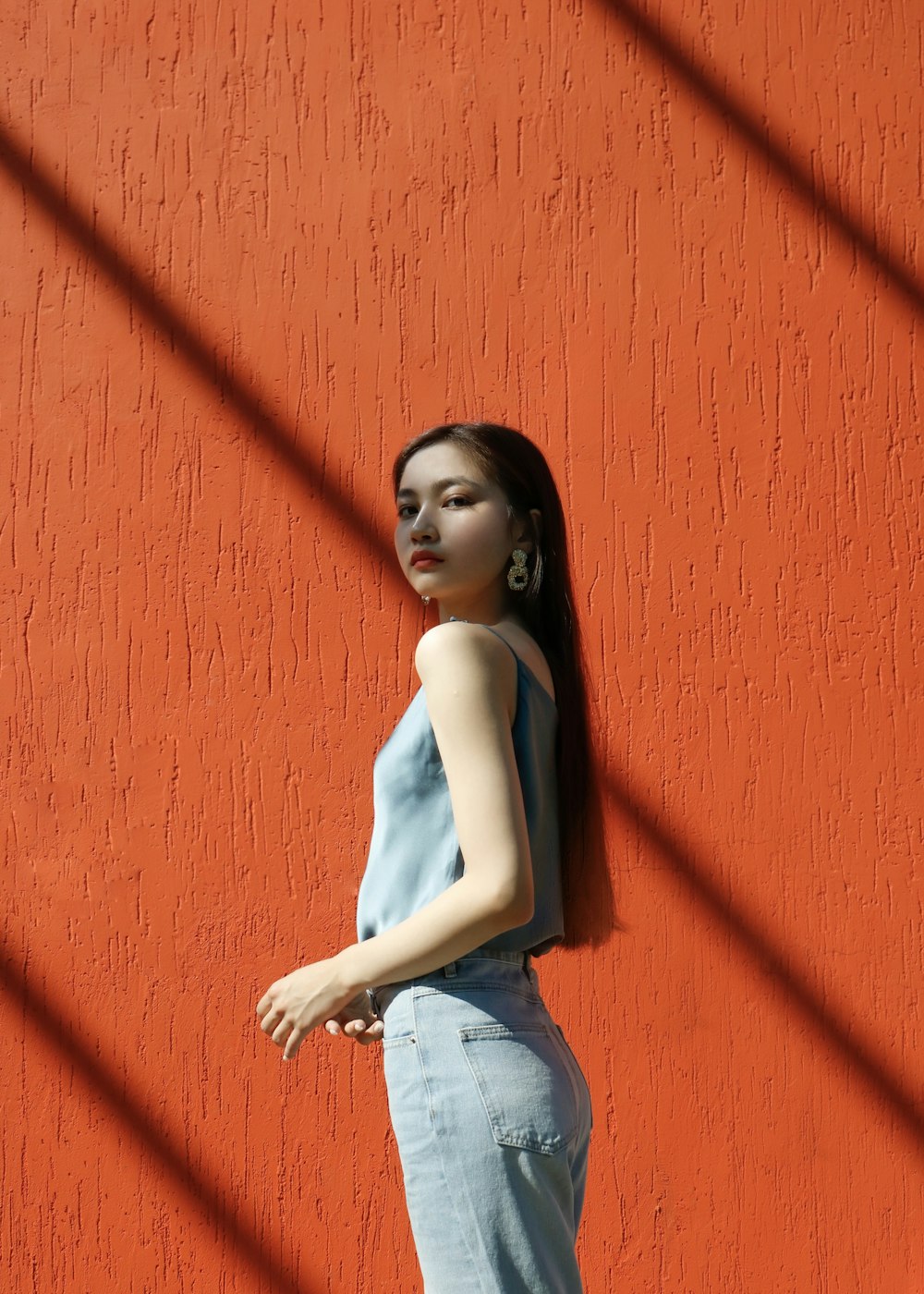 woman in blue top standing beside wall