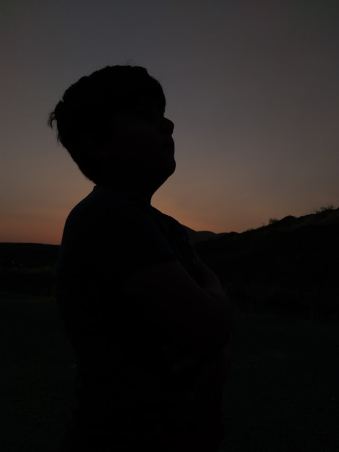 A veteran silhouette stands looking thoughtfully at a sunset.