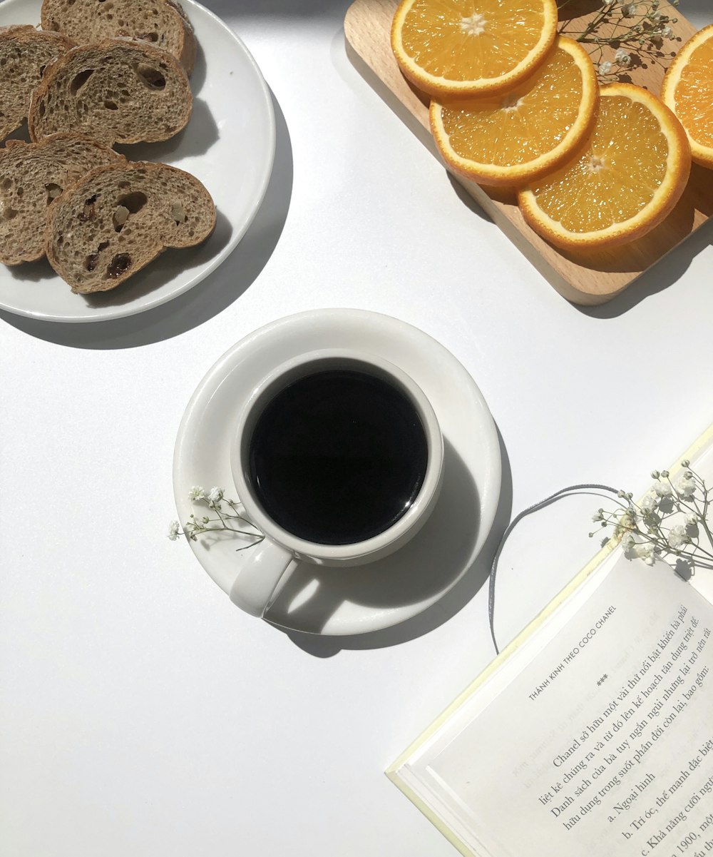 빵과 오렌지 근처의 머그잔에 담긴 커피