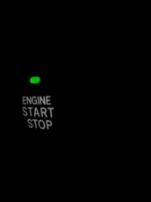 A dark background with illuminated text reading 'ENGINE START STOP', accompanied by a small green light above the text.