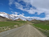 Dirt road leading into a scenic rural landscape with distant mountains.