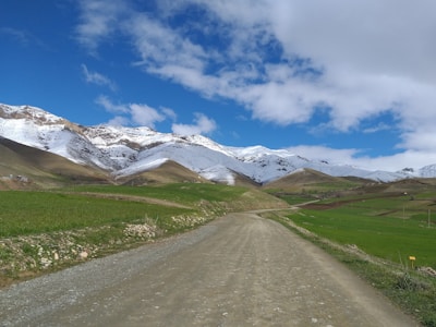 Dirt road leading into a scenic rural landscape with distant mountains.