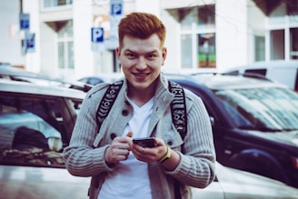 A young tenant smiling while checking rental listings on a smartphone.