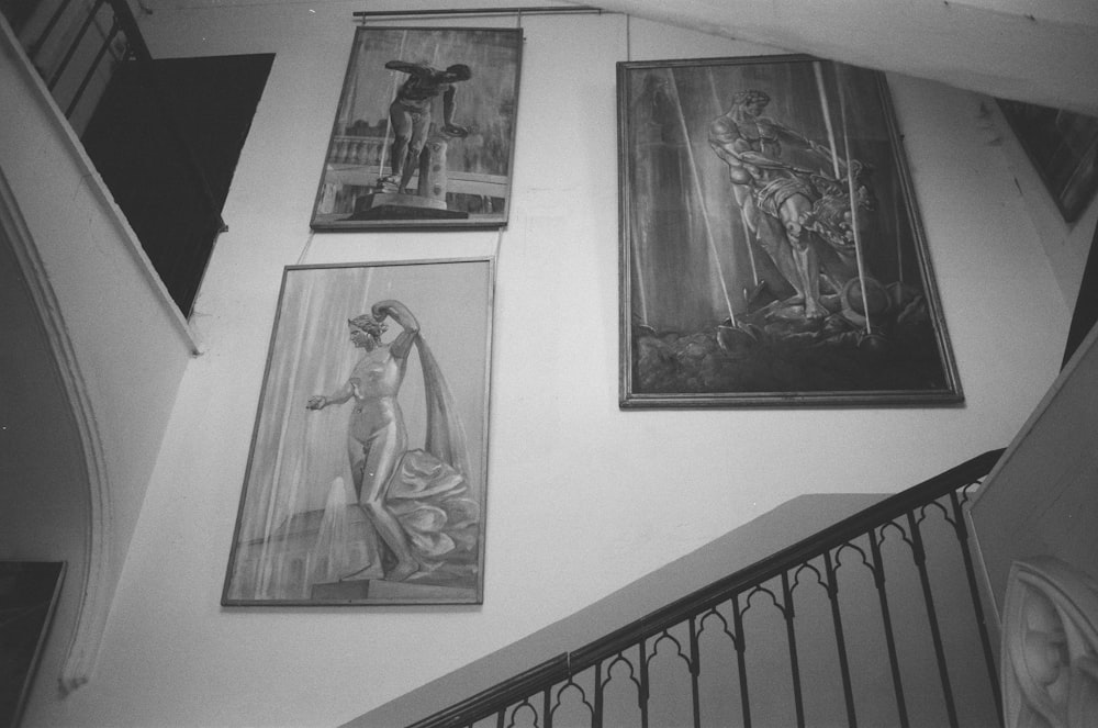 black and white photograph of a staircase with paintings on the wall