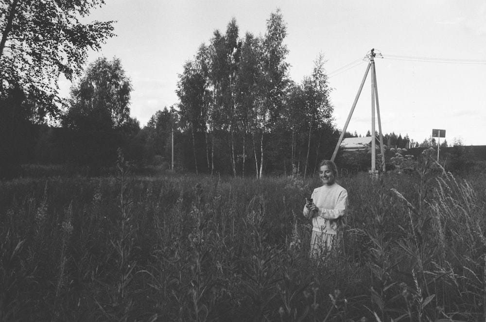 grayscale photography of woman standing on grass during daytime