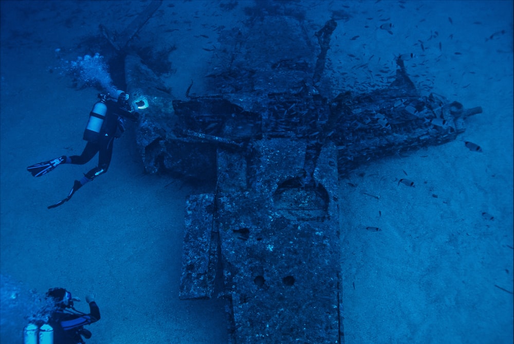 Ein Mann scubas neben einem alten Flugzeug im Ozean