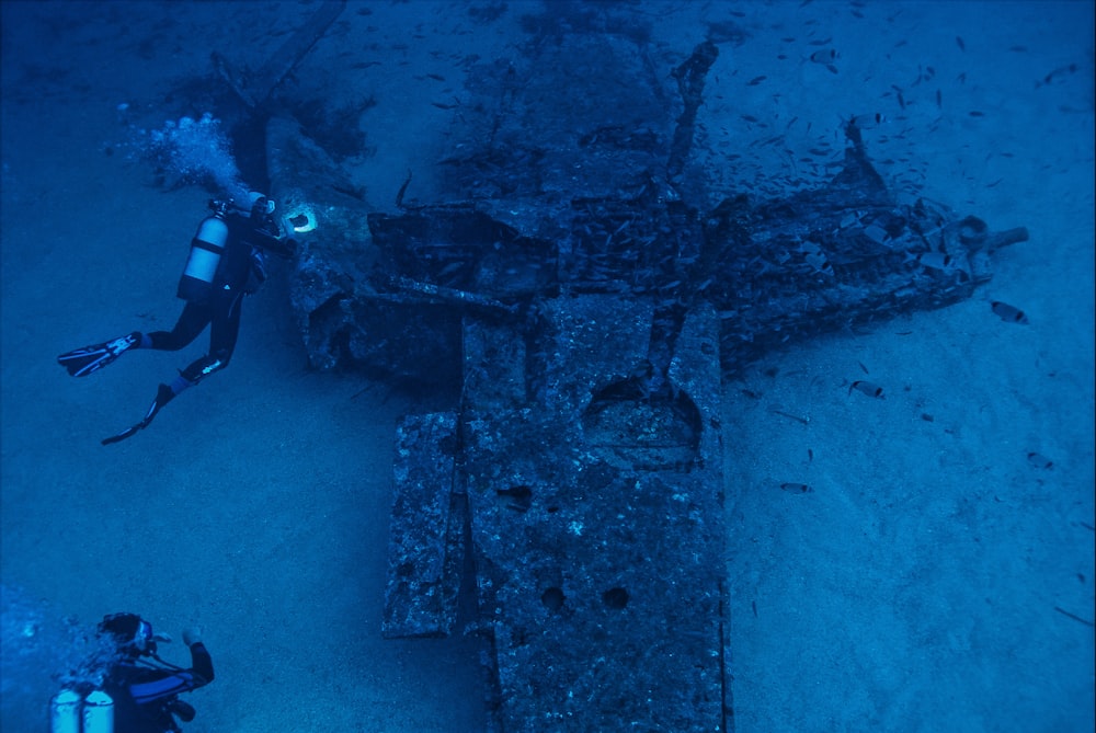 a man scubas next to an old plane in the ocean