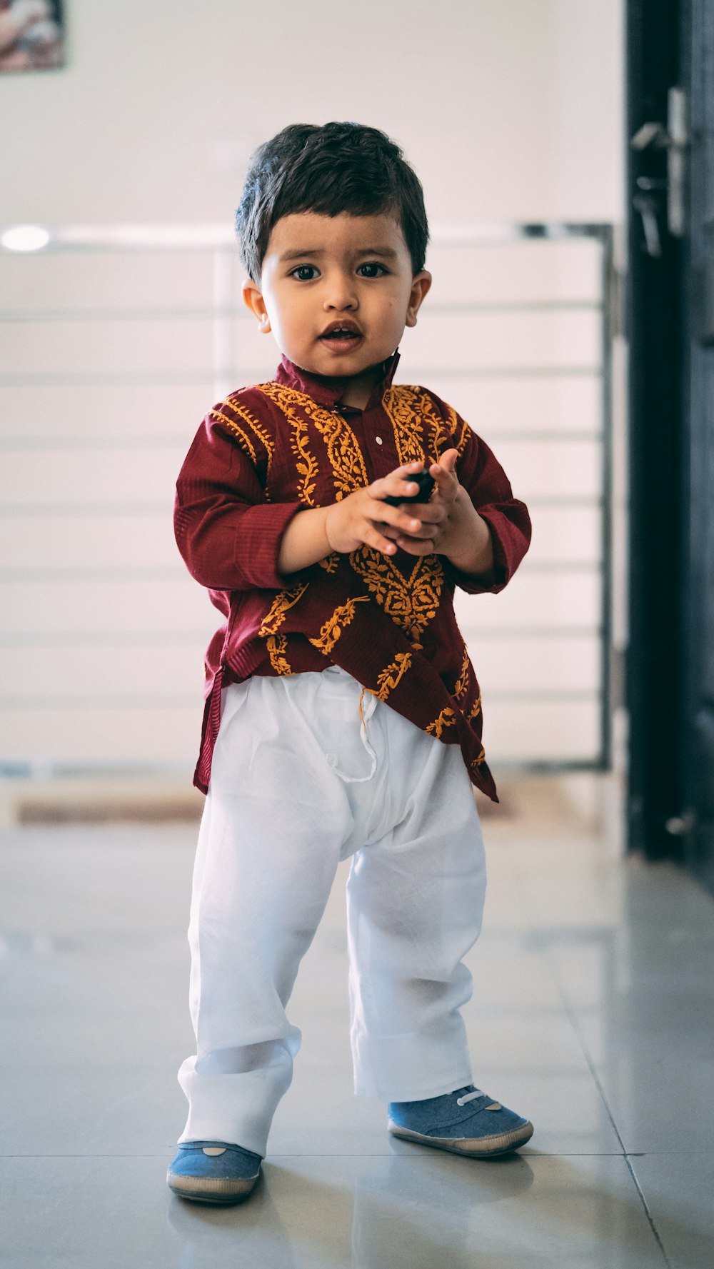 boy wearing maroon and yellow blouse and white pants