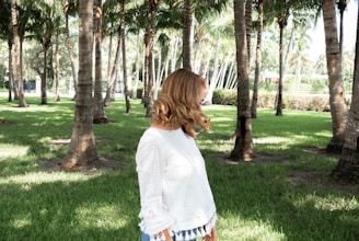 Delicate white mesh top layered over a black sports tank, with sunlight filtering through palm leaves